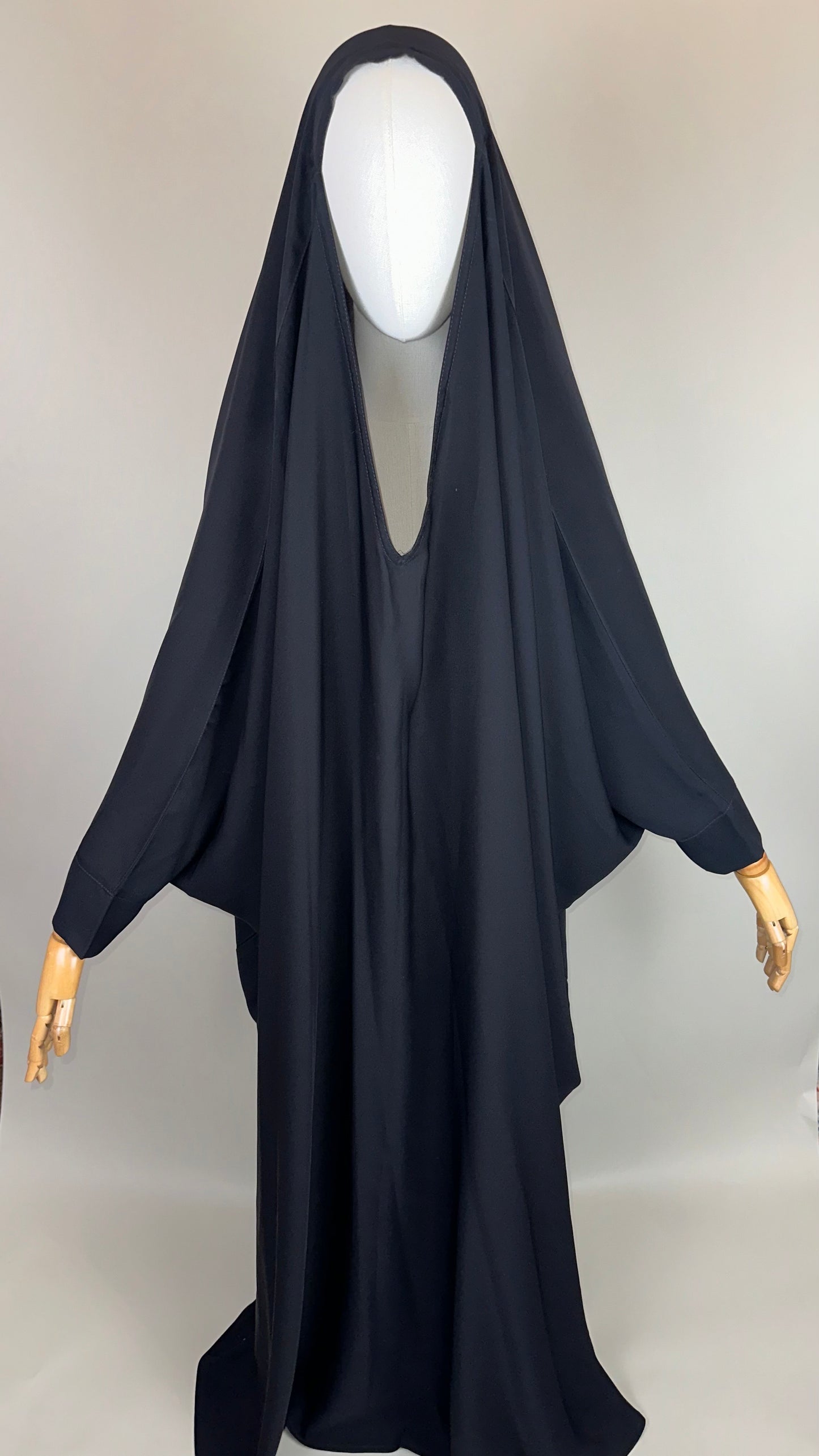 Black abaya on mannequin with wooden hands, modest Islamic dress, studio background