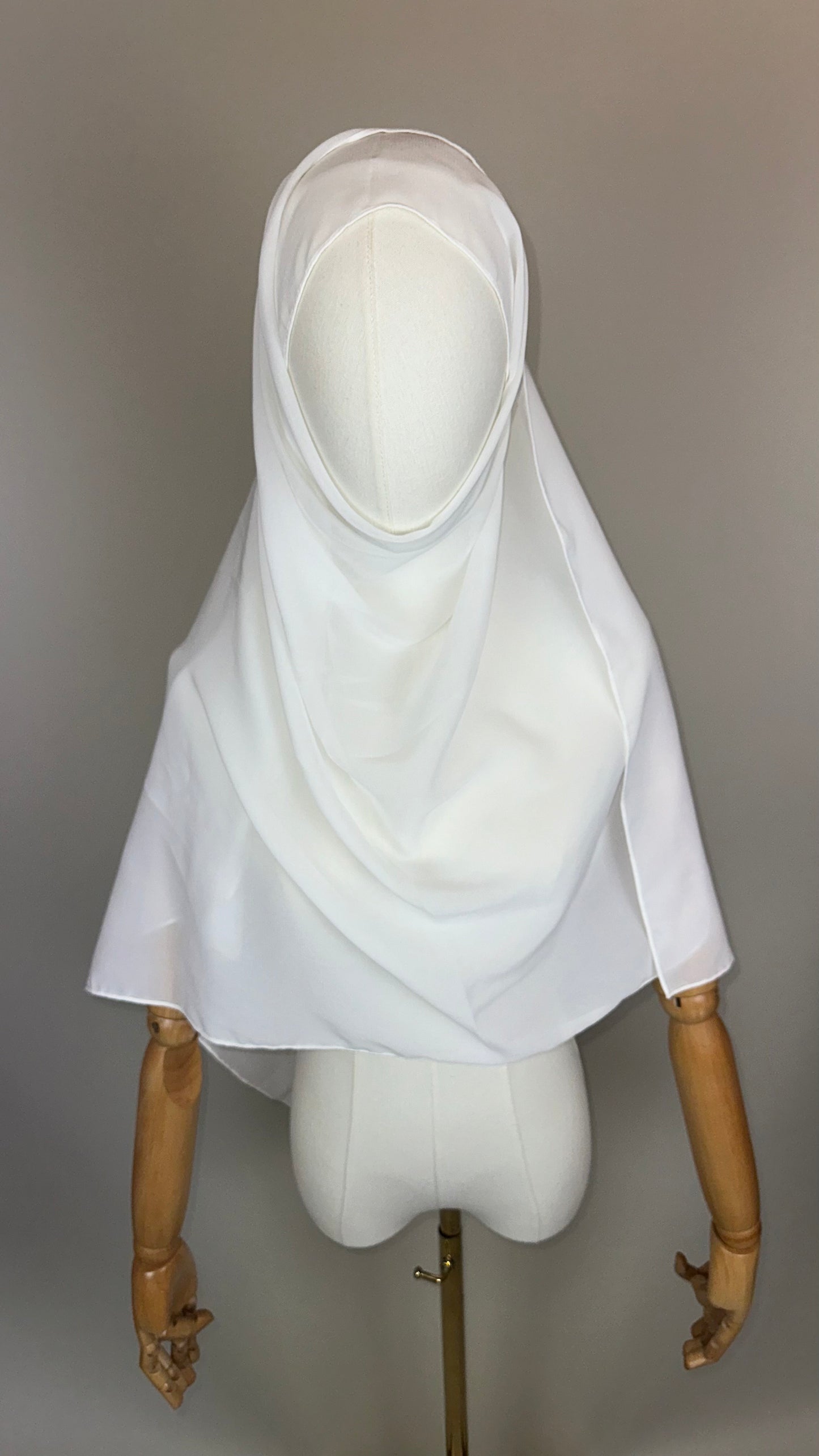 White hijab draped on a mannequin with wooden arms, plain background