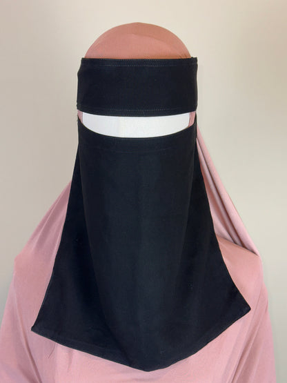 Black niqab on mannequin with pink hijab, Islamic modest wear display