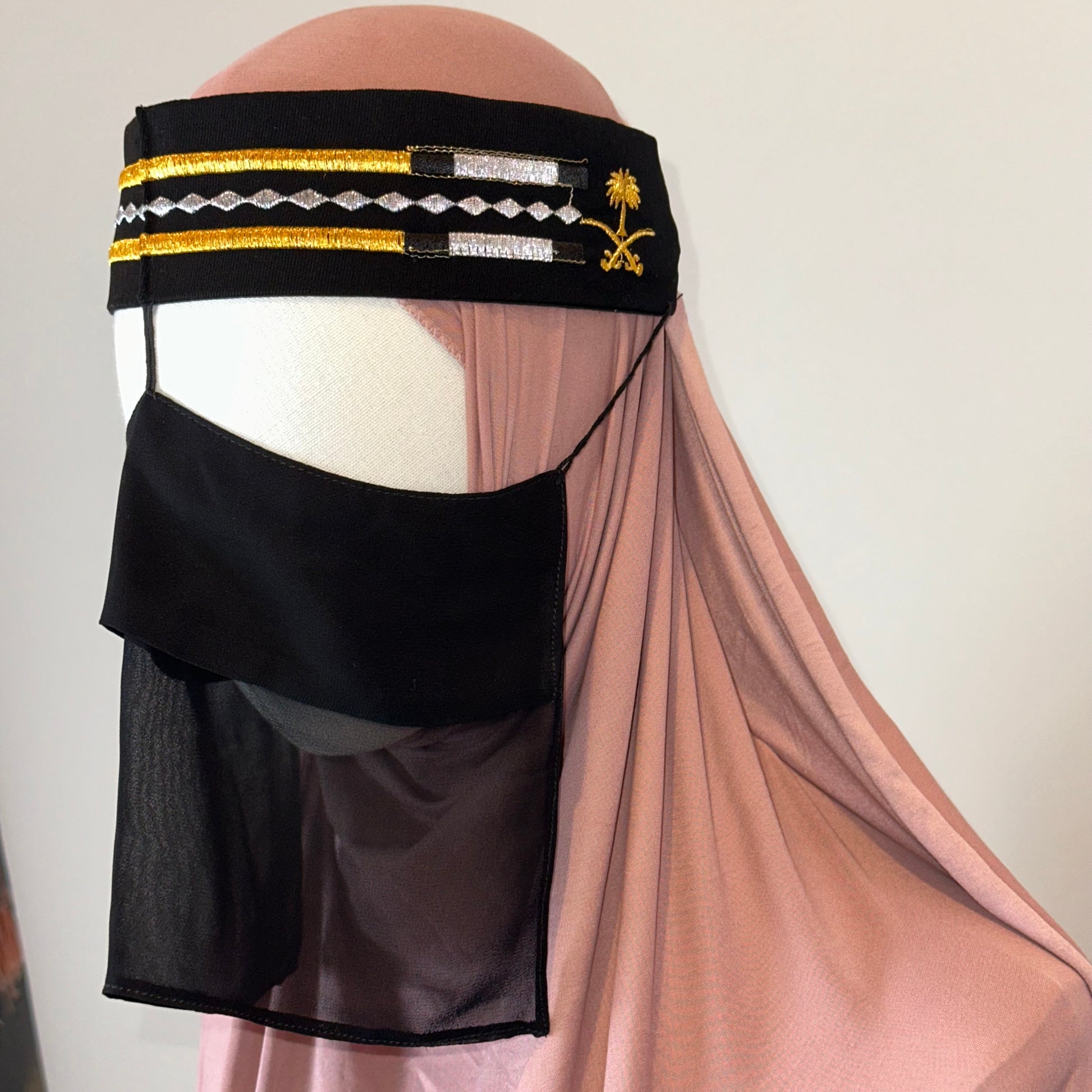 Mannequin with pink hijab, black veil, and Saudi-inspired embroidered black headband