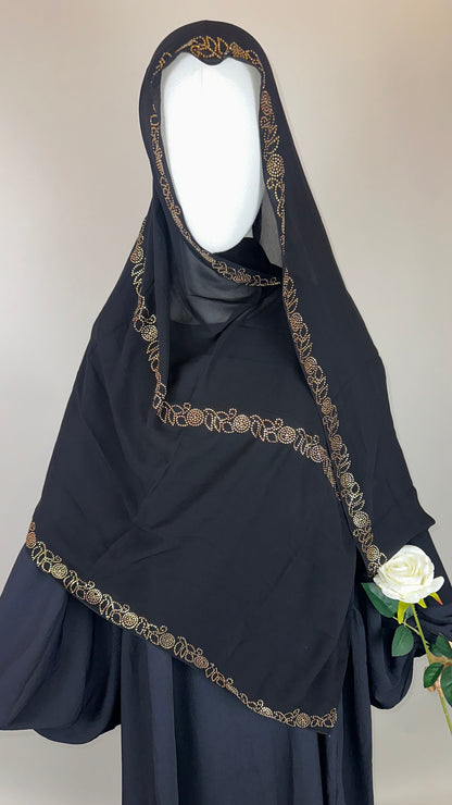 Black khimar with gold embroidery, mannequin holding white rose, modest Islamic fashion