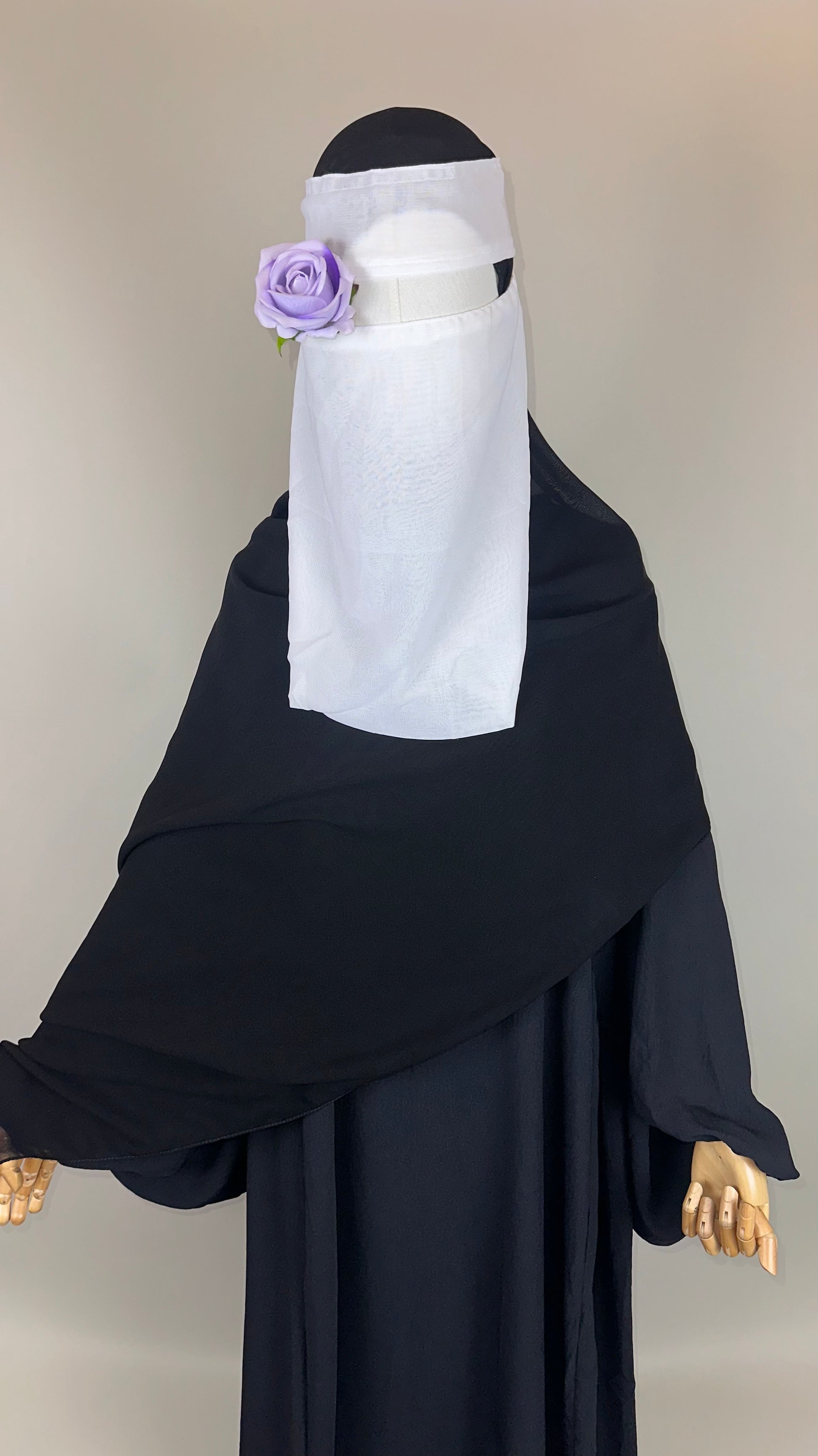 Mannequin in black abaya and white niqab with purple rose accessory