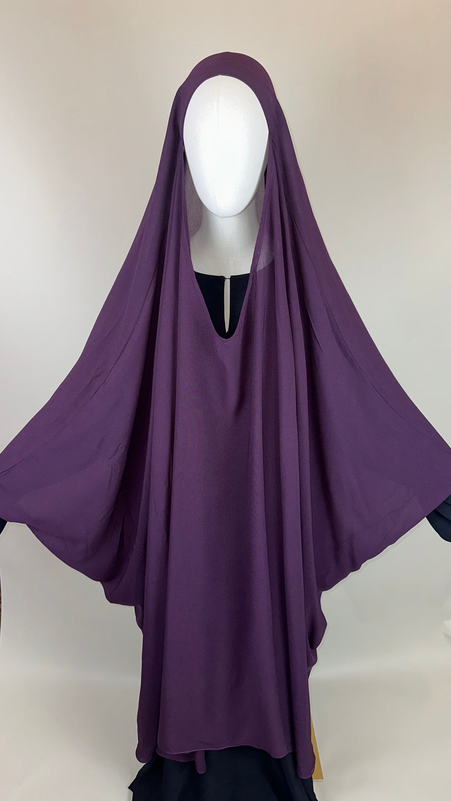 Mannequin displaying a purple khimar hijab against a plain background