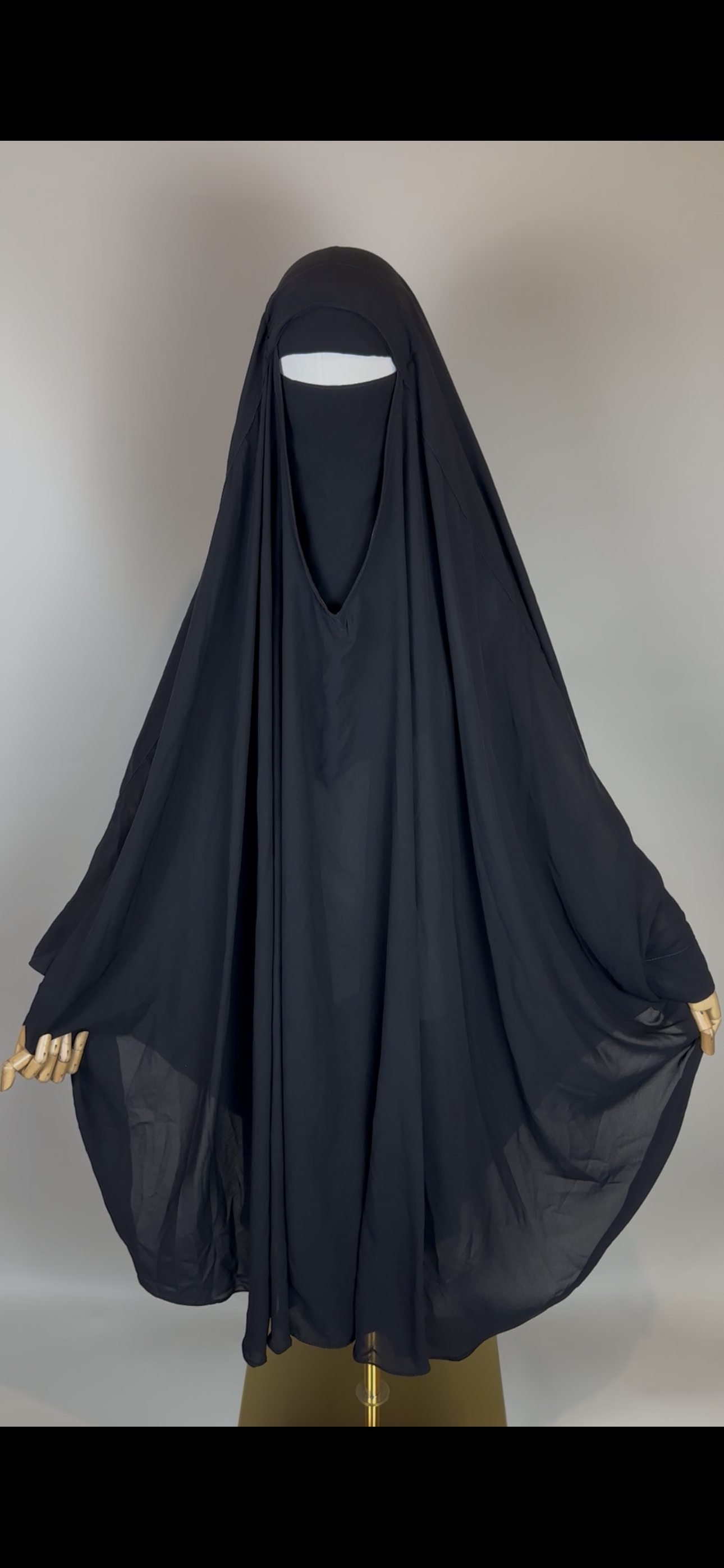 Black Saudi niqab abaya on mannequin with flowing fabric, modest Islamic clothing