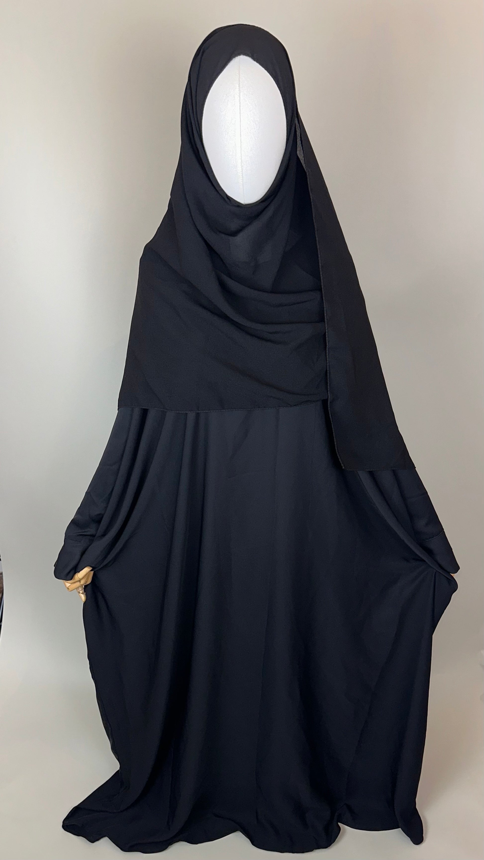 Black khimar abaya on mannequin, modest Islamic clothing, plain background