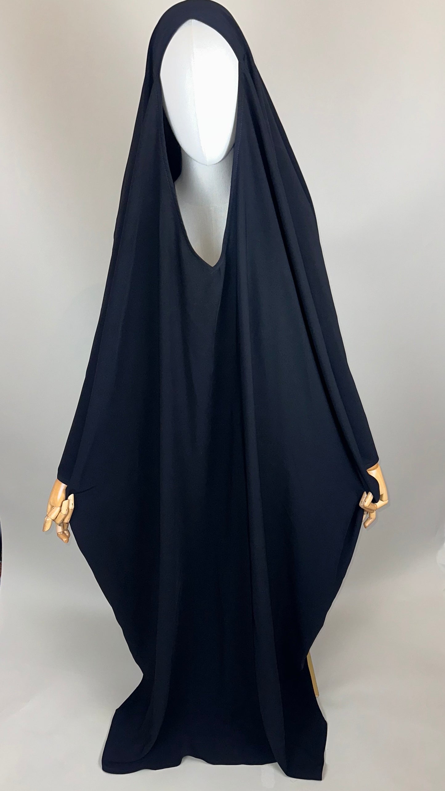 Black overhead abaya on mannequin with wooden hands, modest Islamic fashion