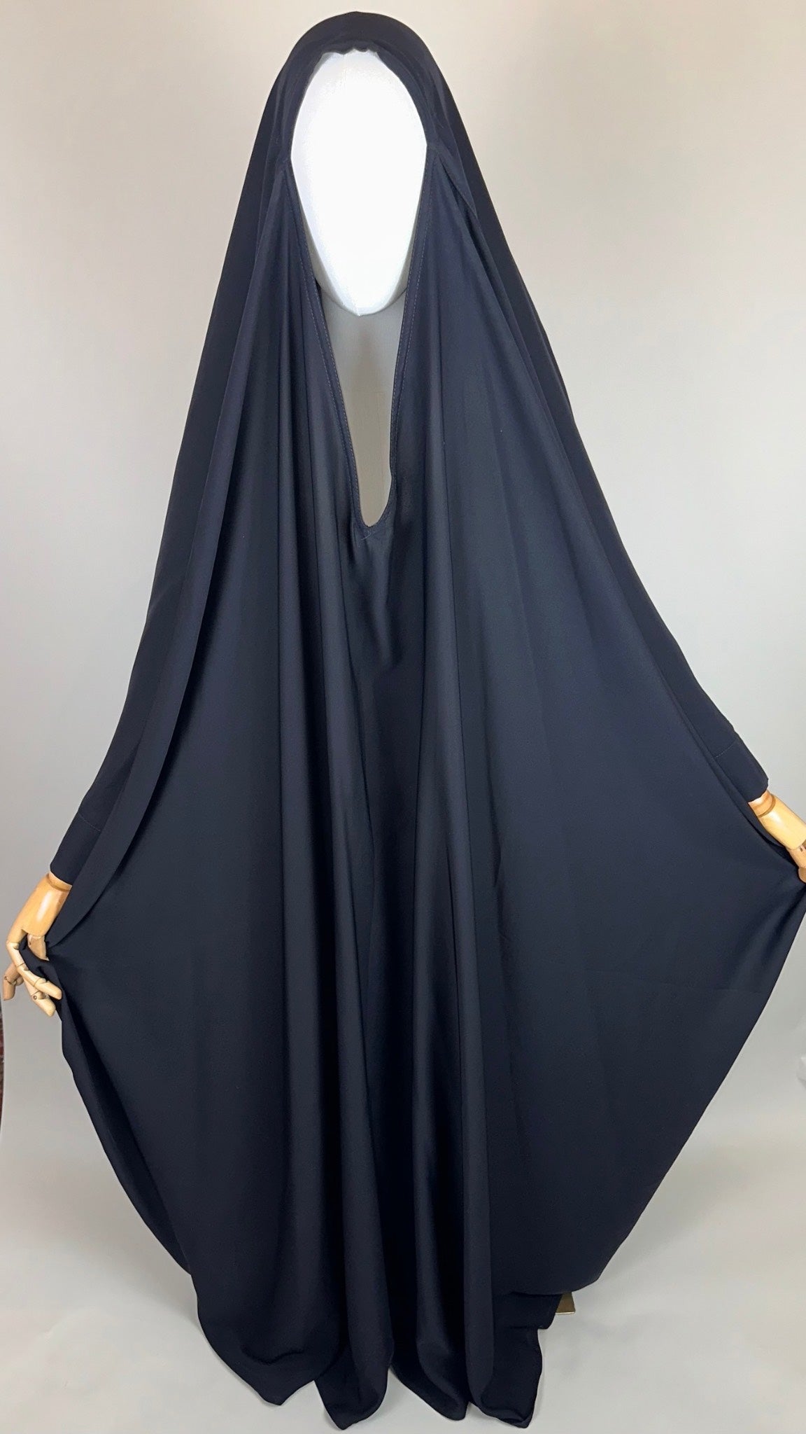 Plain black Islamic chador draped on mannequin in studio setting